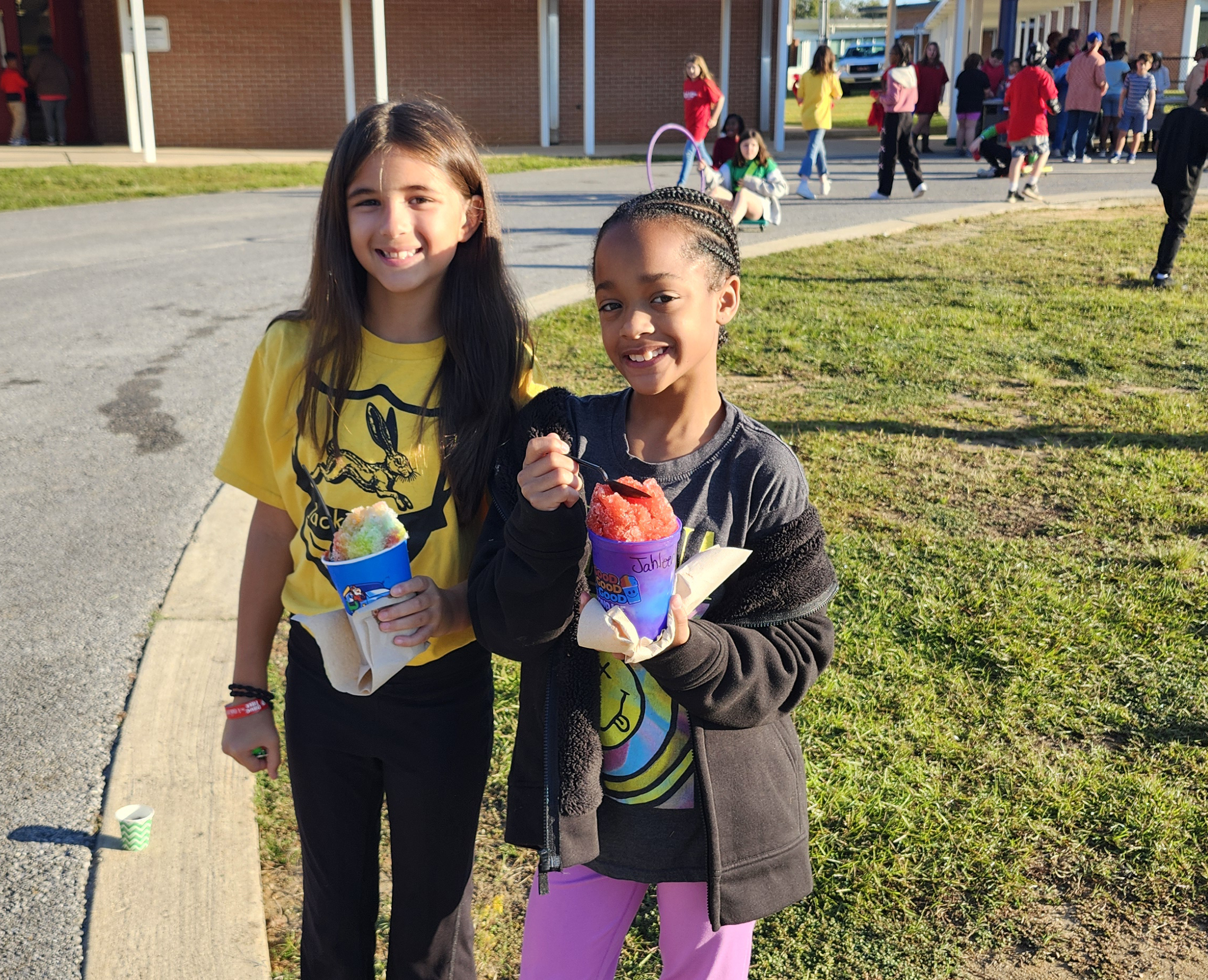 Two girls outside eating snowcones.
