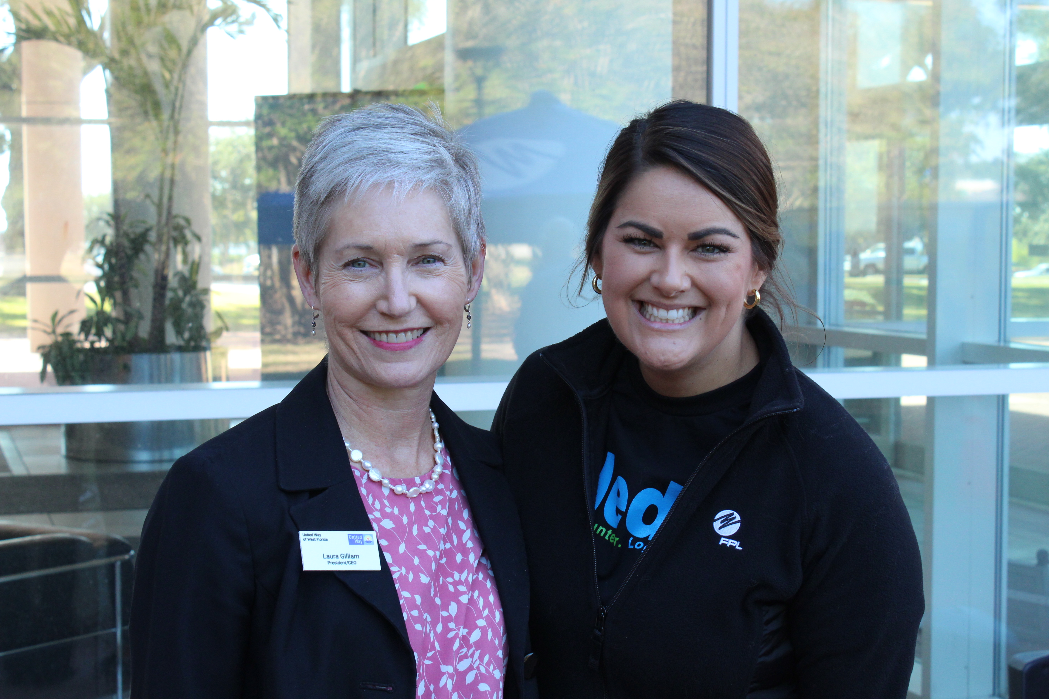 Laura Gilliam  (UWWF president/CEO) with Dana Hall from FPL during the 2023 FPL workplace campaign. 2 women outside one in a pink shirt and black cardigan, the other in a black hoodie and black cardigan with iPledge, the FPL workplace giving shirt on