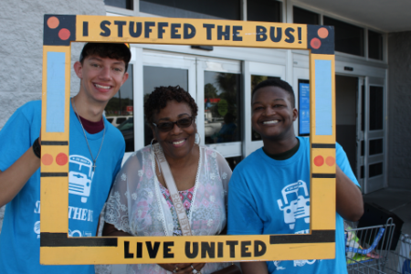 Volunteers inside sign that says I stuffed the Bus - Live United