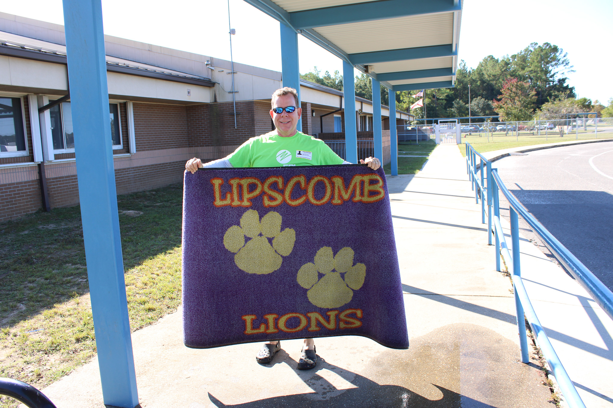 FPL Volunteer at Lipcomb elementary holding rug that was pressure washed