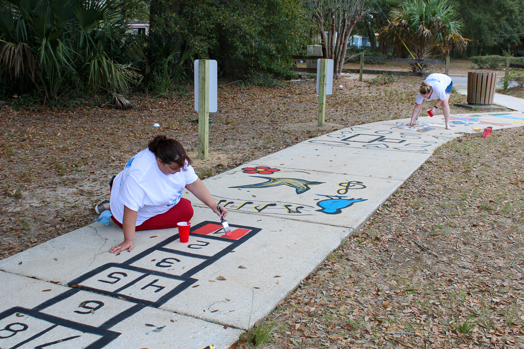 Volunteer paints sidewalk