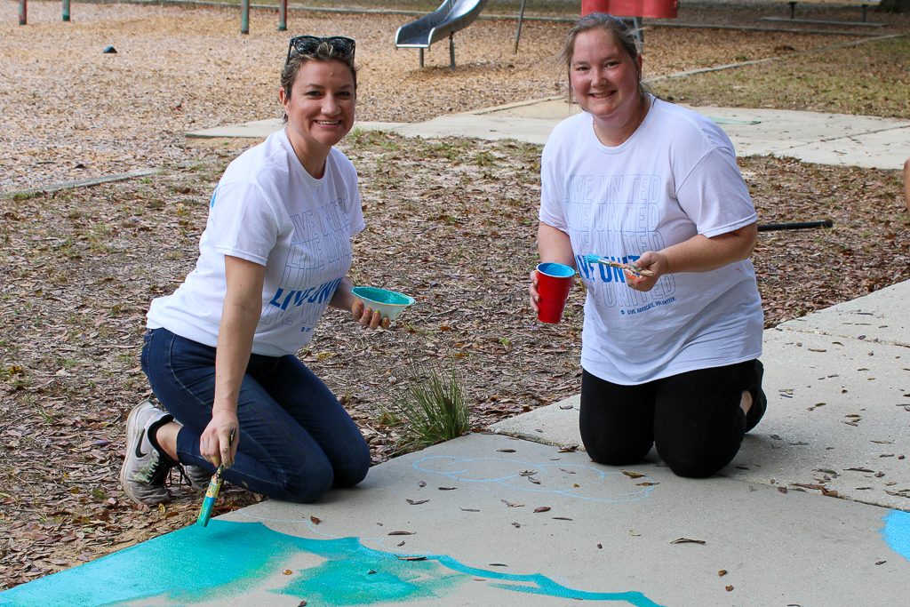 Volunteers paints sidewalk