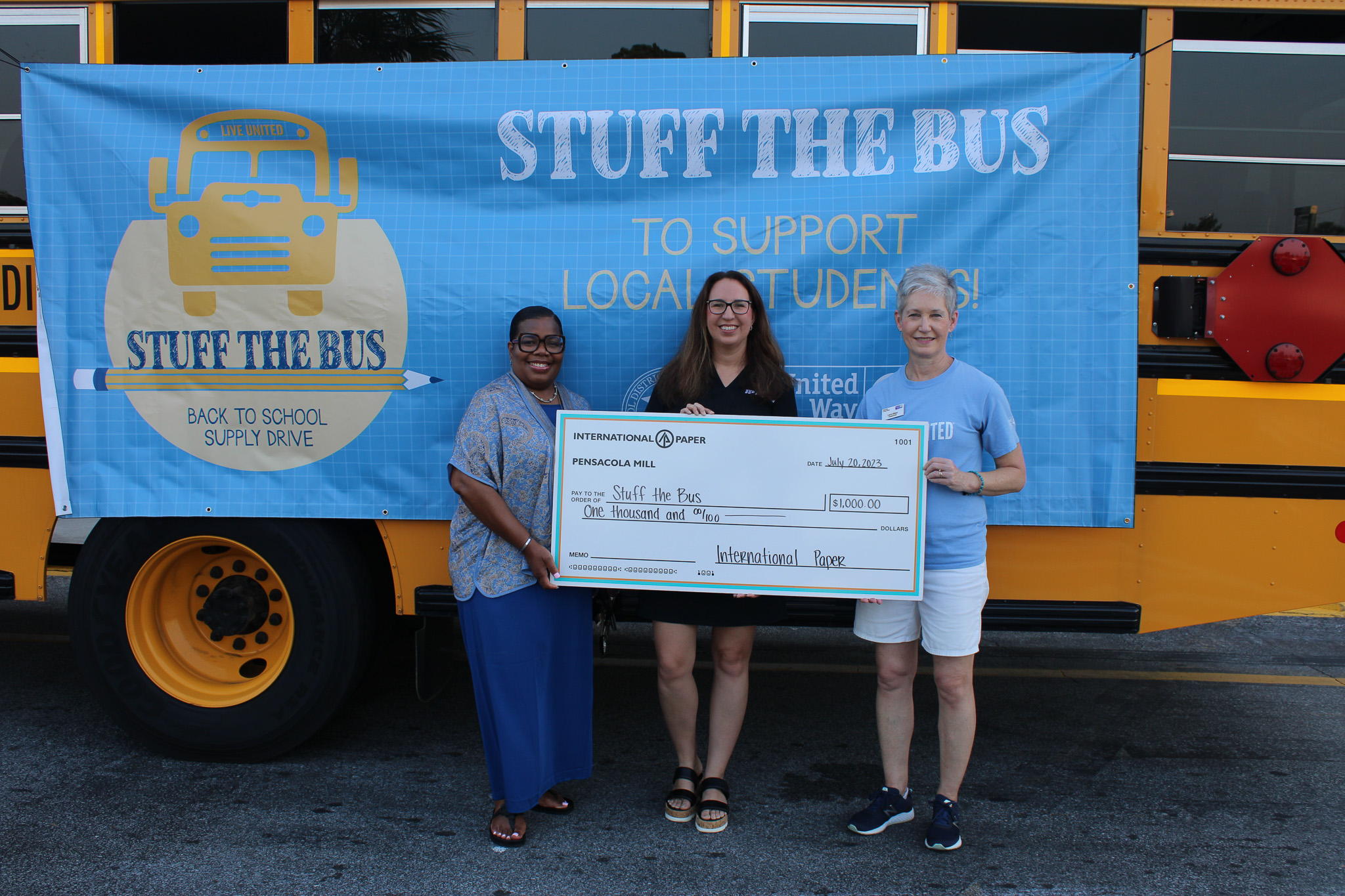International Paper holding $1.000 check in front of Stuff the Bus Bus