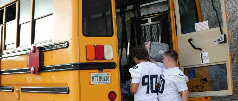 Teenage boys loading school supplies on a bus.