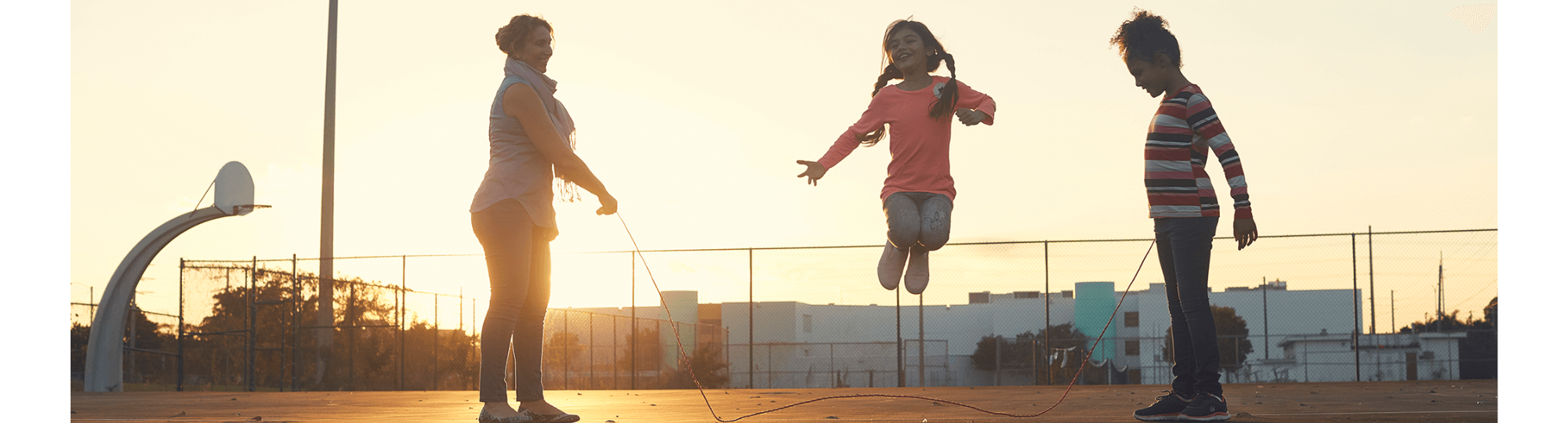 A family jumping rope at sunset.