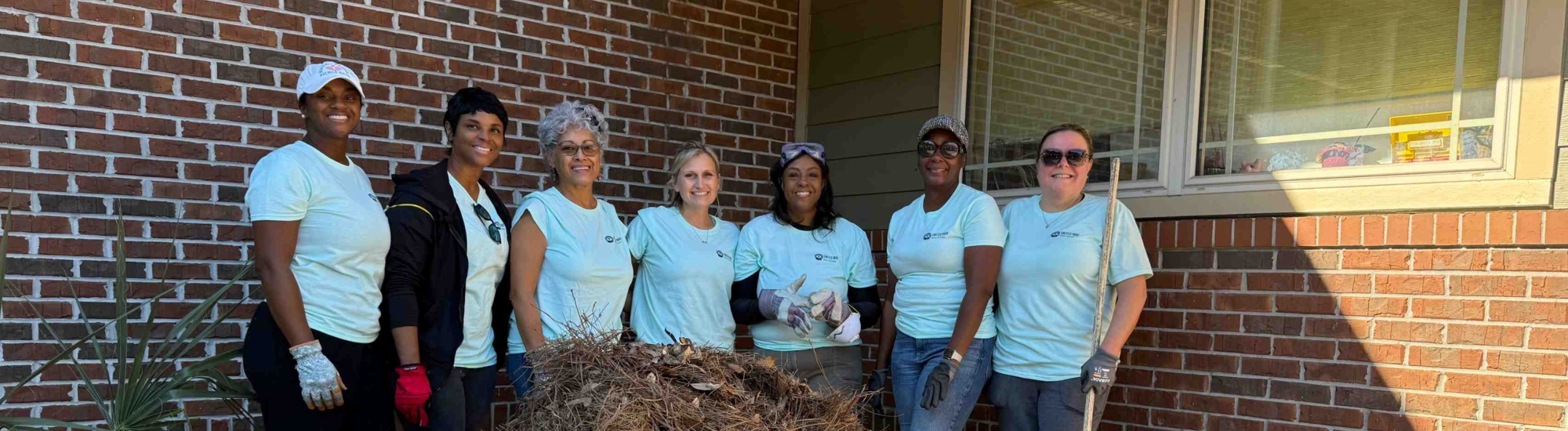 People standing behind a wheelbarrow holding a rake.