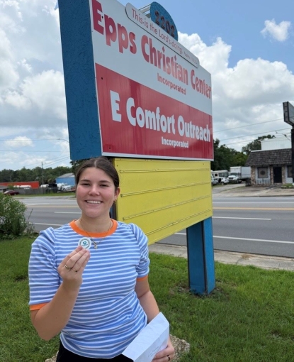 Erica holding a token in front of the Epps Christian Center sign.