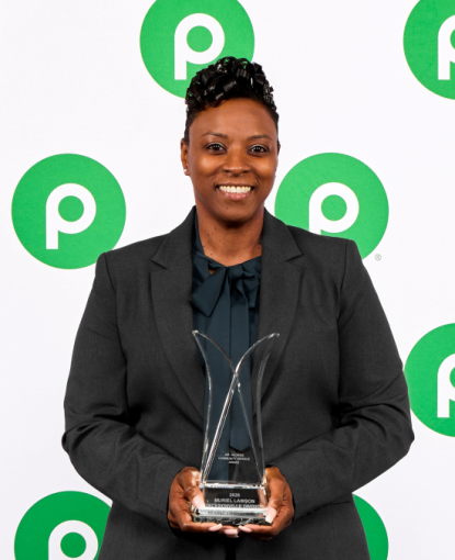 Woman in a green suit holding an award.